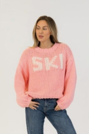 Model wearing chunky pink SKI sweater by Lyla + Luxe, styled with blue jeans on white backdrop – perfect après-ski knit