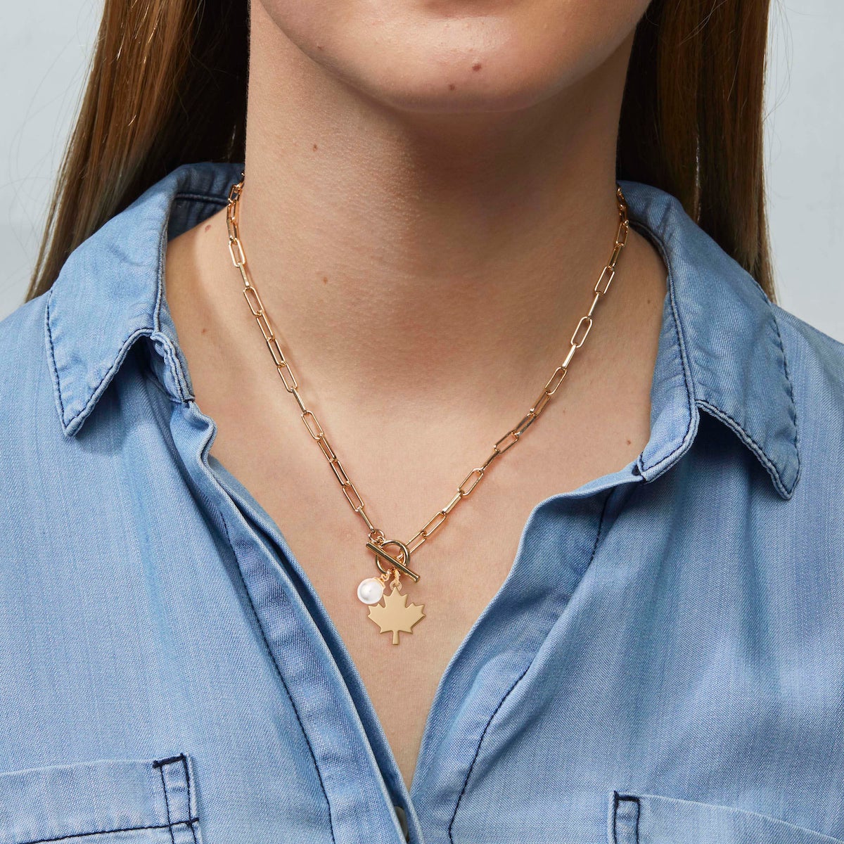 Gold Maple Leaf Toggle Necklace with pearl charm styled on model in chambray shirt – Foxy Originals Canadian jewelry