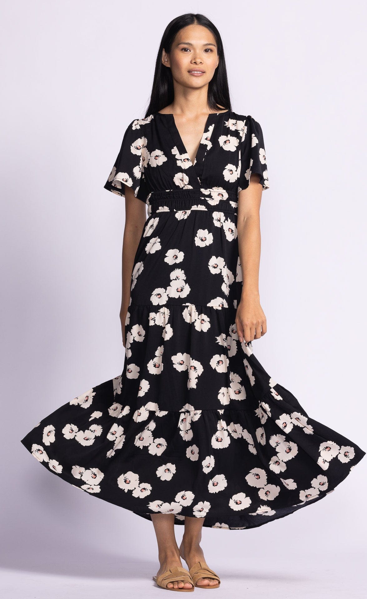 Model wearing the Margaret dress by Pink Martini from Lemonberry in Aurora Ontario, pairing it with brown sandals and performing a slight twirl displaying the skirts bell flair.