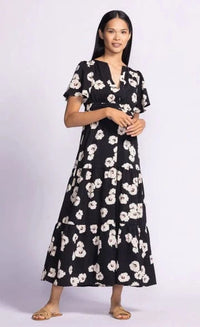 Model wearing the cute spring floral dress by Pink Martini, with its black base and beautiful pink and white flowers throughout, available at Lemonberry, ON.