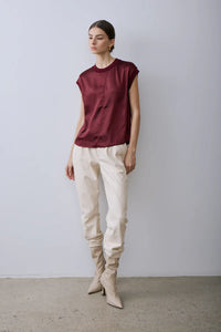Woman wearing Melissa Nepton's Gaylor top in Red Wine and beige pants with high-heeled shoes against a plain background