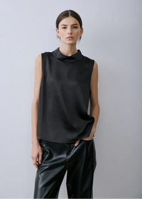 Person wearing a Melissa Nepton's black sleeveless top and black pants against a light grey background