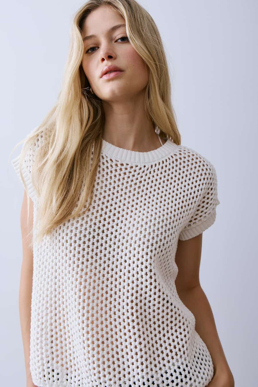 Woman wearing a white knit top against a plain background