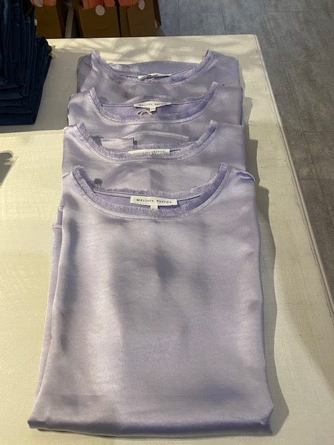 Folded lavender Willow tops, by Melissa Nepton on a table inside Lemonberry boutique