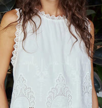 White lace-trimmed Melissa Nepton Rio top worn by a person with a plant background