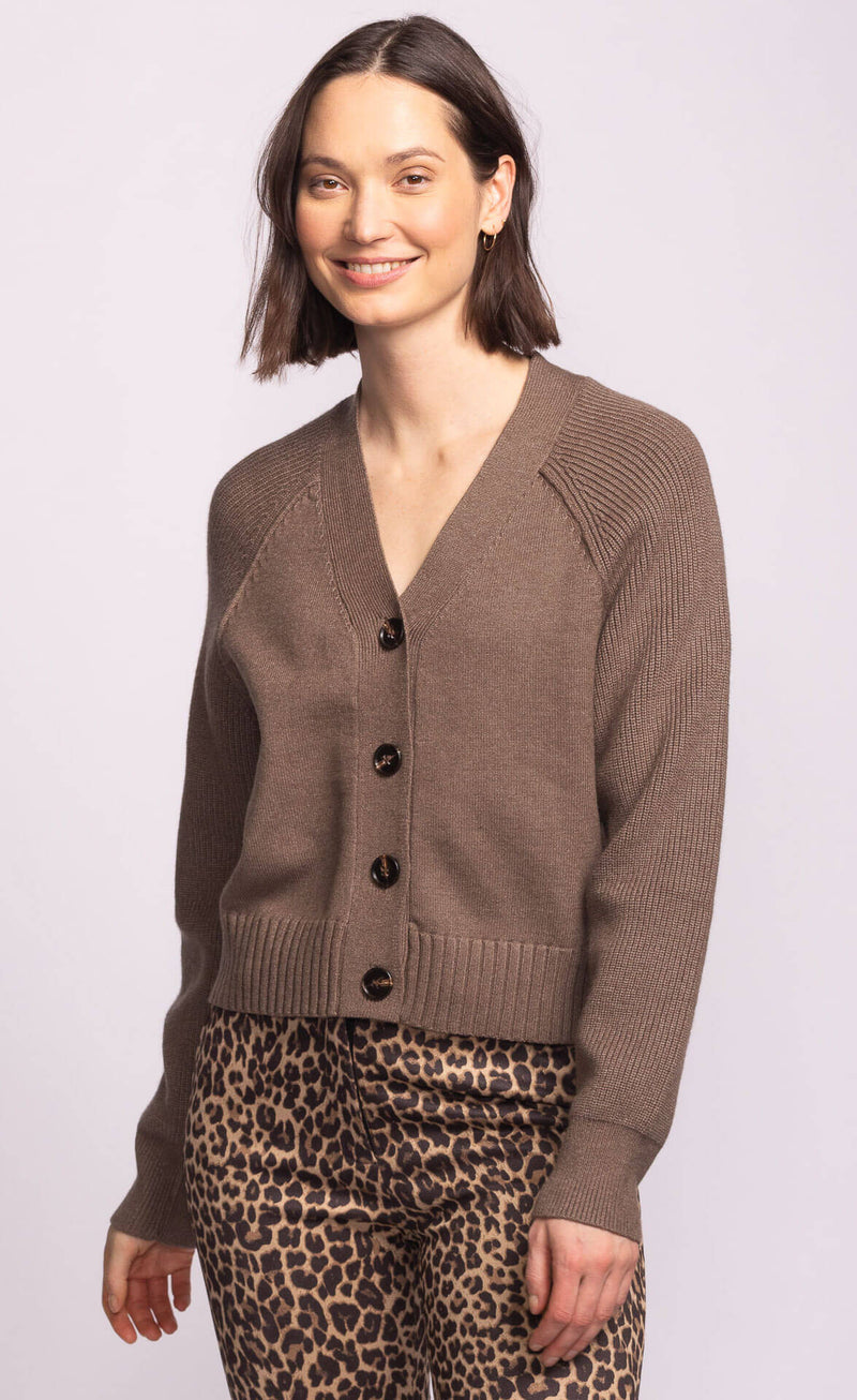 Model smiling in the Monterey Sweater, lightweight neutral taupe cardigan with button front and cropped silhouette.