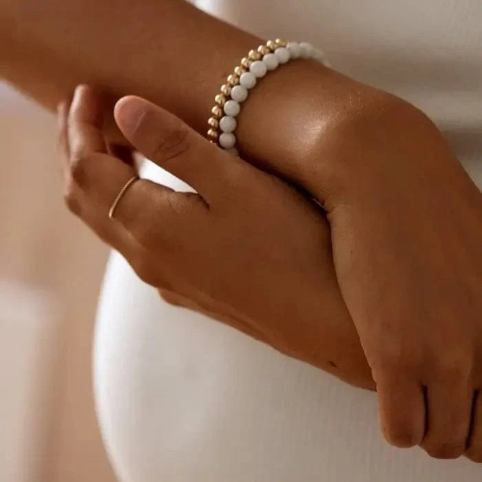Close-up of moonstone and gold beaded bracelet stacked on wrist — available at Lemonberry