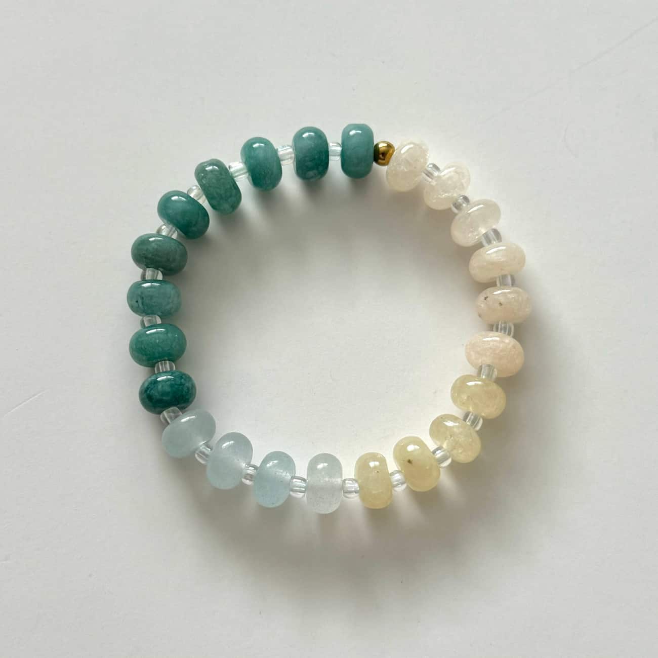 Namaste Jewellery Dania Bracelet Drift Pearl stretch bracelet with teal pearl and pale blue beads flat lay on white background