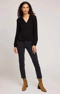 Woman wearing a black blouse, black pants, and brown boots on a white background