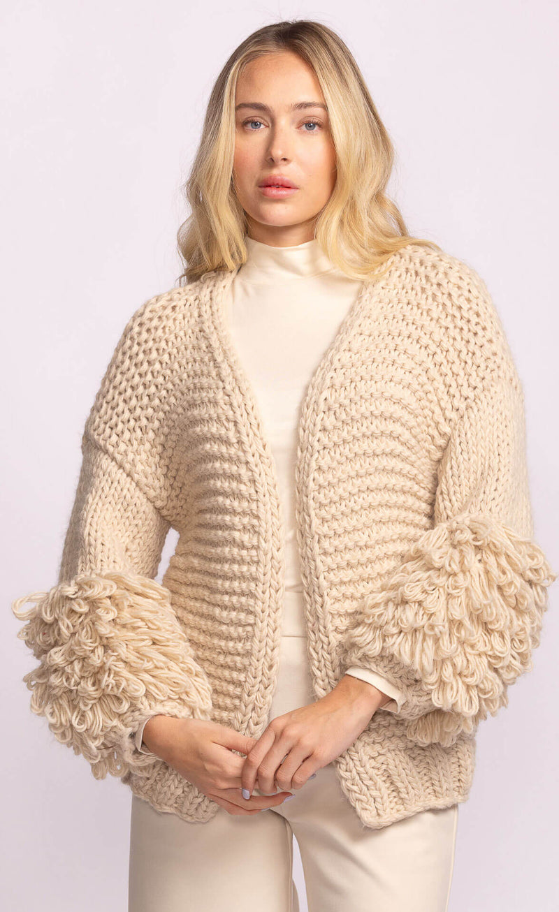 Model wearing Pink Martini Palermo Sweater in soft cream, open-front knit with textured loop sleeves – available at Lemonberry Aurora and online.