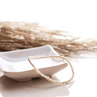 Pearl and gold intention bracelet styled on white ceramic dish with dried grass — available at Lemonberry in Aurora, ON