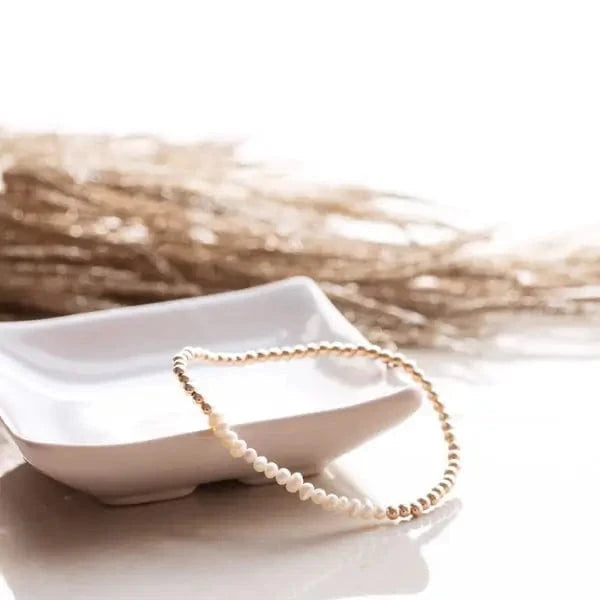 Pearl and gold intention bracelet styled on white ceramic dish with dried grass — available at Lemonberry in Aurora, ON