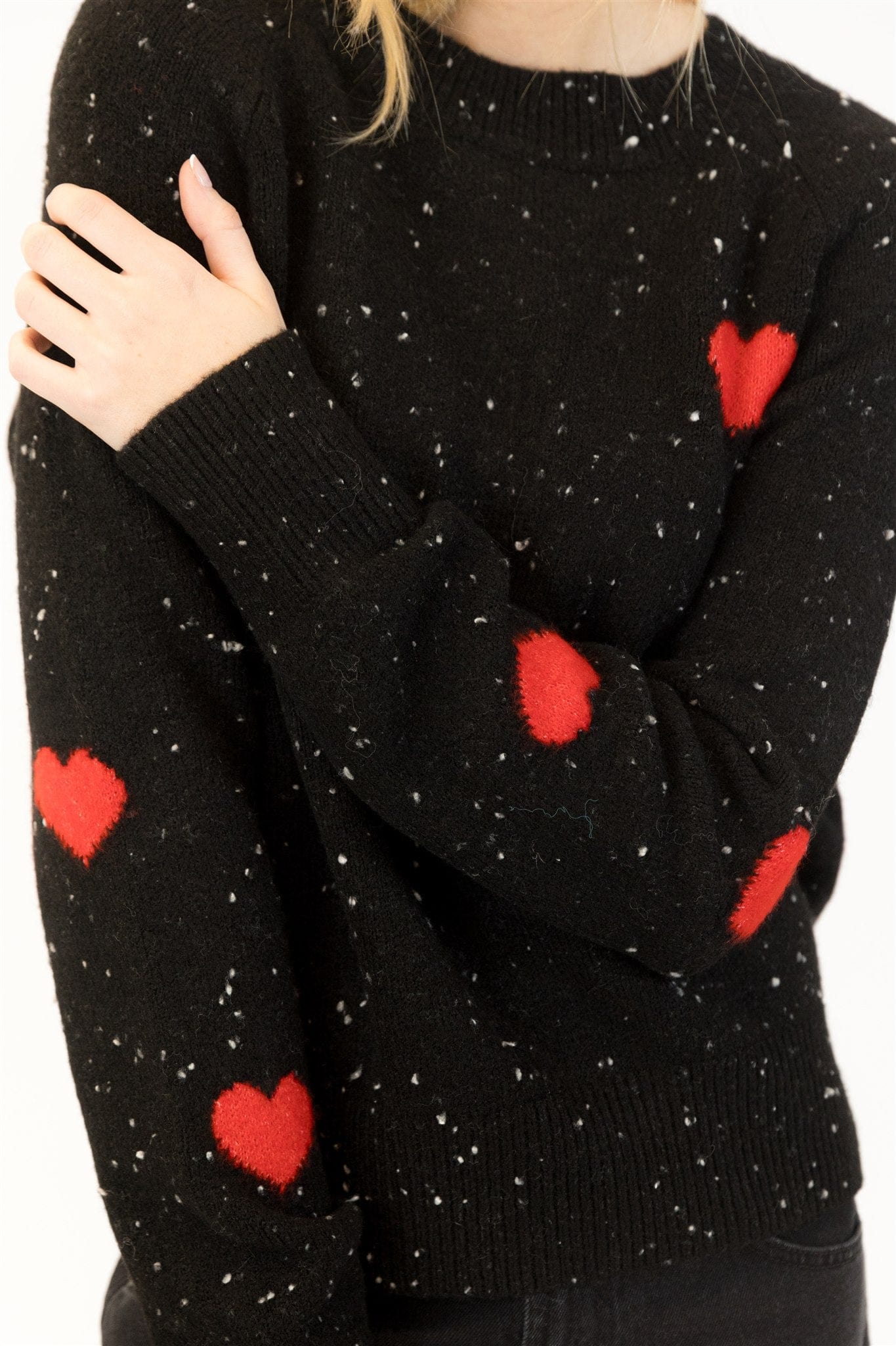 Close-up of red heart elbow patches on speckled black Lyla & Luxe sweater