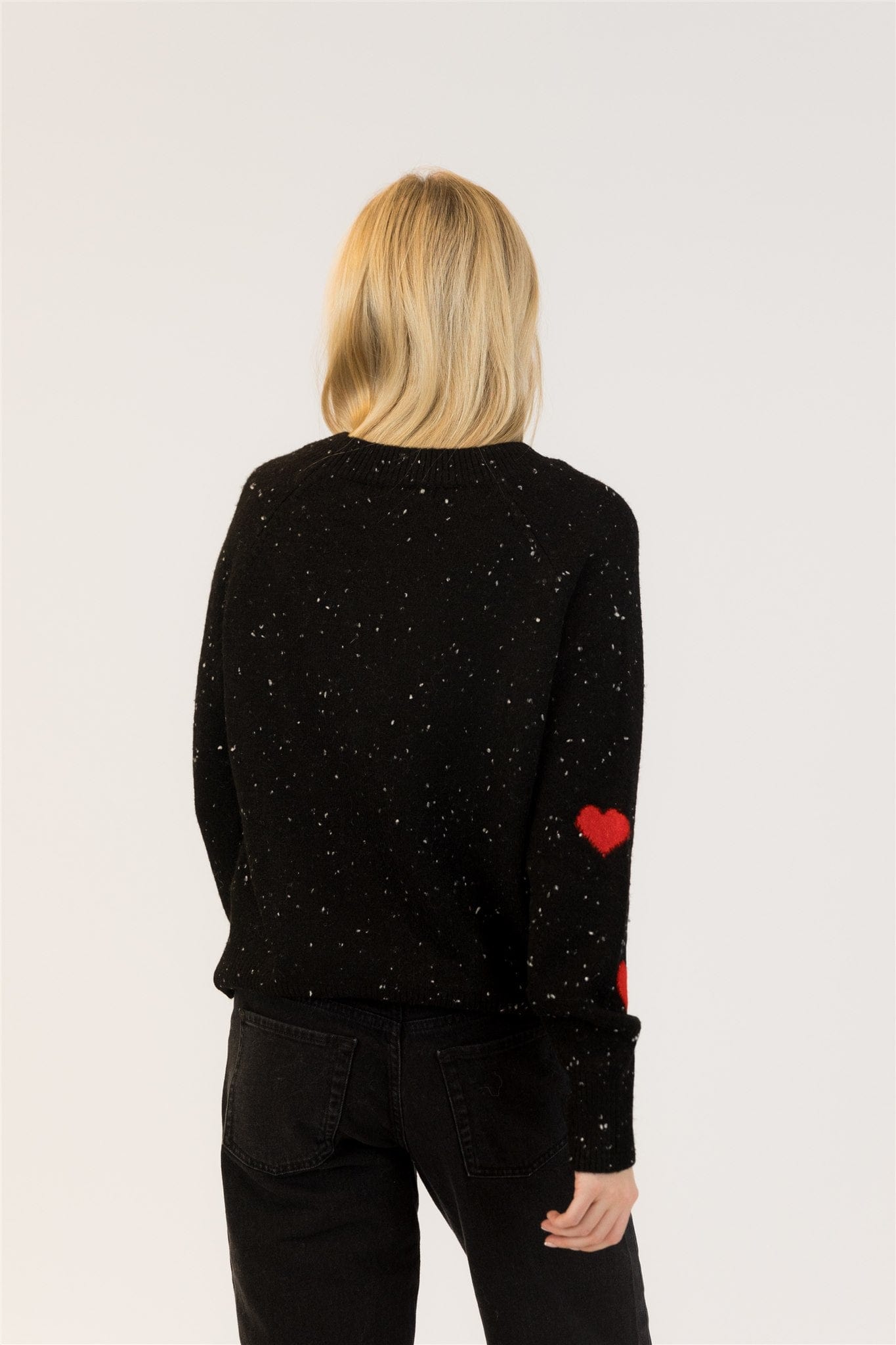 Back of Philippa pullover with speckled black knit and red hearts on sleeves