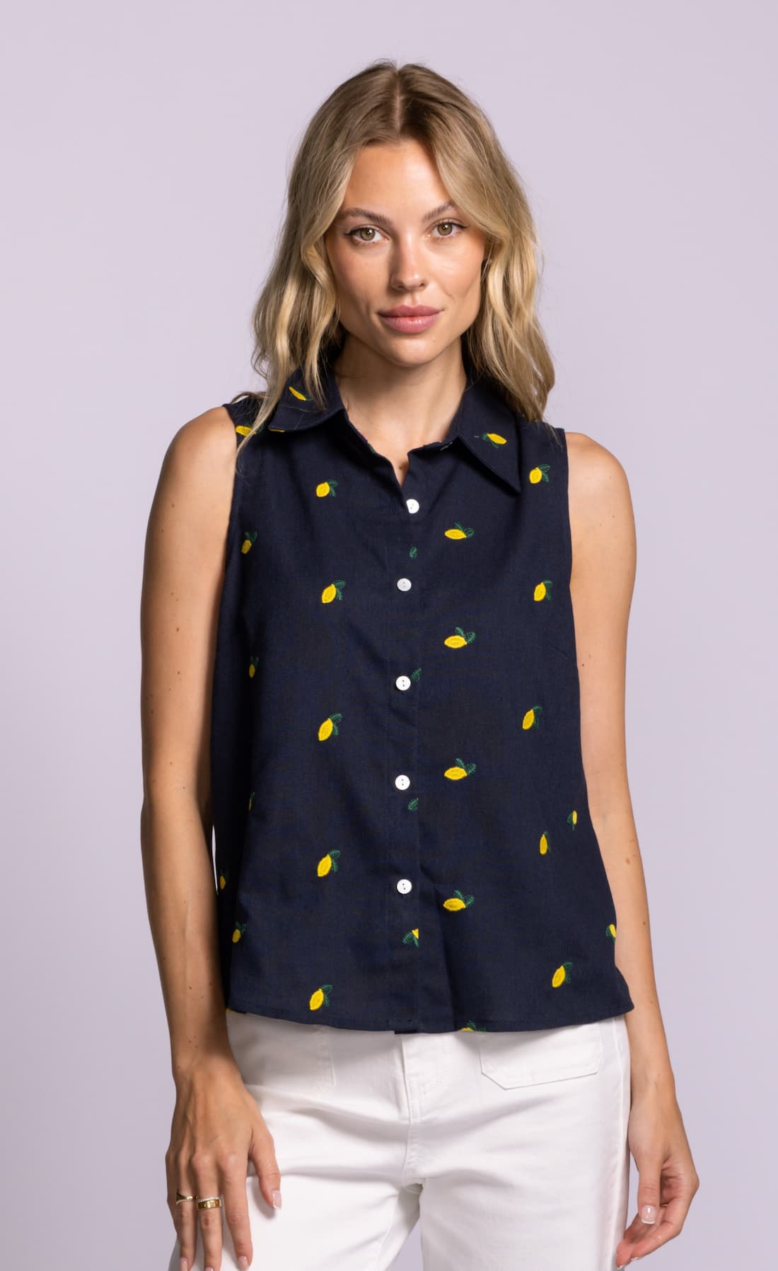 Woman wearing a Pink Martini navy sleeveless shirt with yellow lemon pattern on a light gray background