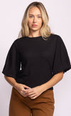 Model in Pink Martini Lita Top black textured blouse, puff sleeve front view.