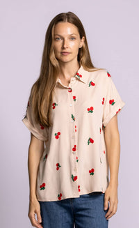 Pink Martini Mon Cherry blouse in beige styled with denim, embroidered cherry detail visible.