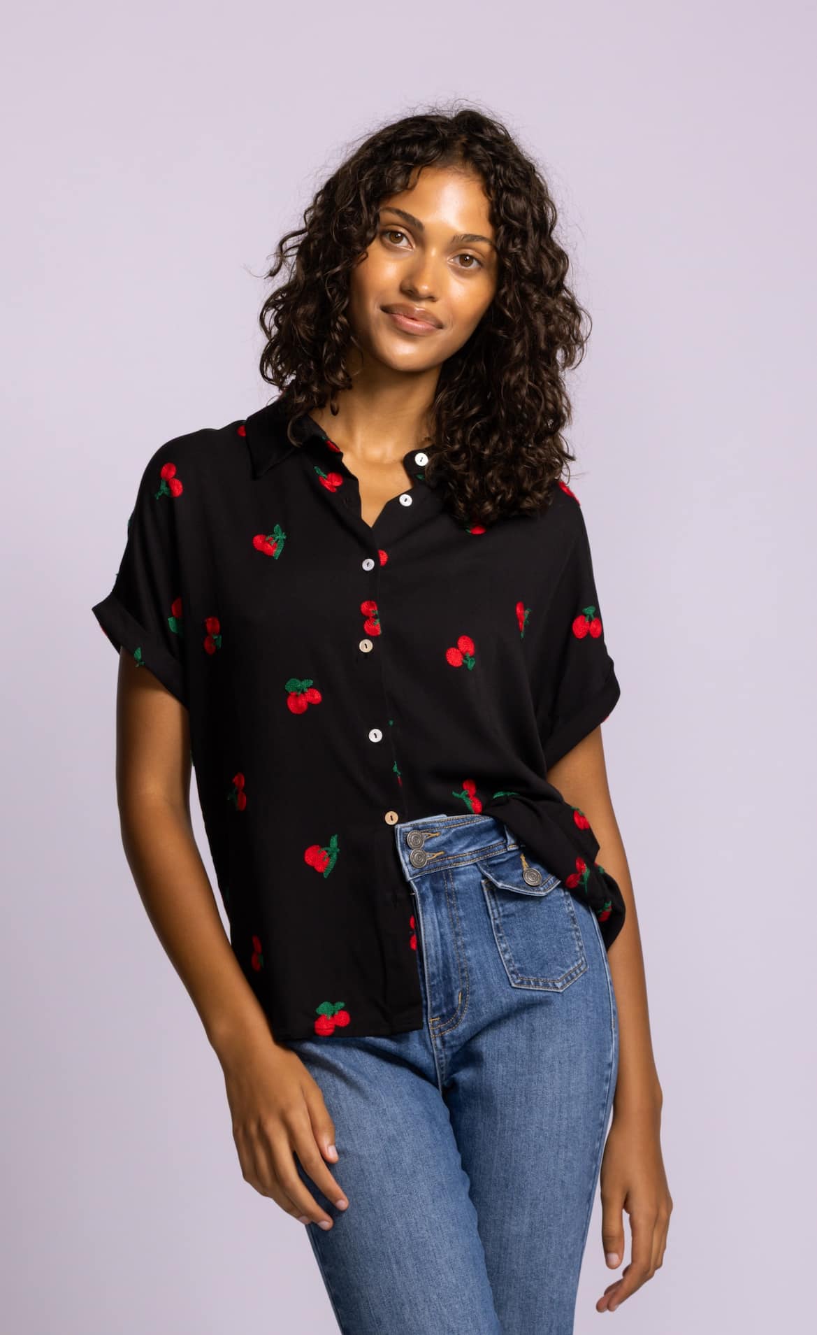 Pink Martini Mon Cherry blouse in black styled with blue denim, embroidered cherry detail visible.