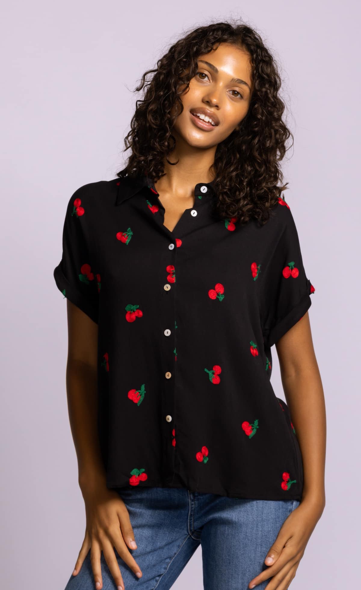 Pink Martini Mon Cherry blouse in black with embroidered red cherry detail, short sleeve button front styled with denim at Lemonberry Aurora.