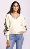 Pink Martini Pavia Sweater in cream, featuring black floral embroidery on balloon sleeves and whipstitch neckline detail, styled with denim.