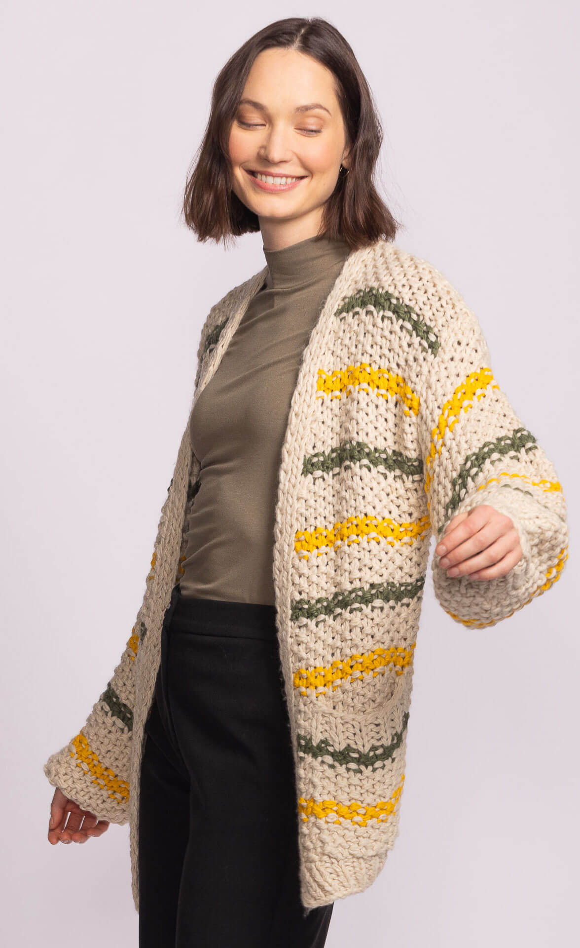 Side view of Samoa Sweater by Pink Martini with chunky knit stripes and bubble sleeves, styled with black pants