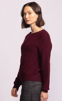 Woman wearing a burgundy sweater against a plain background