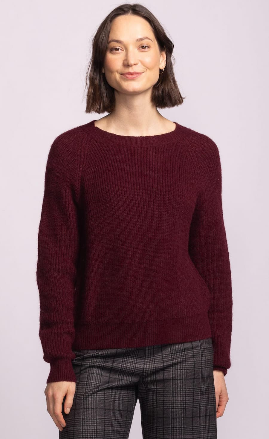 Woman wearing a burgundy sweater against a light purple background