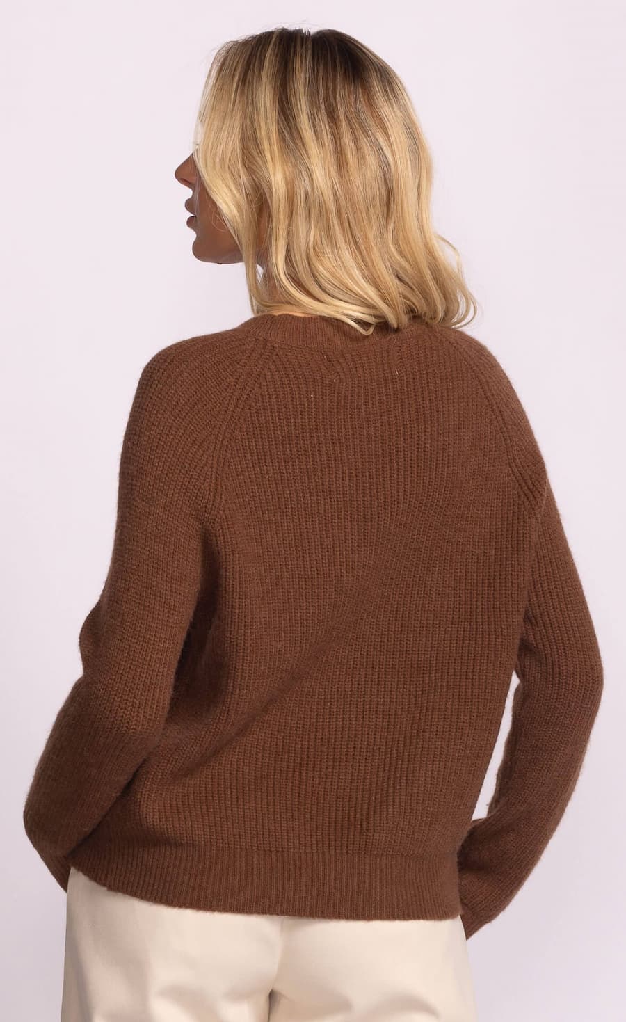 Person wearing a brown sweater on a white background