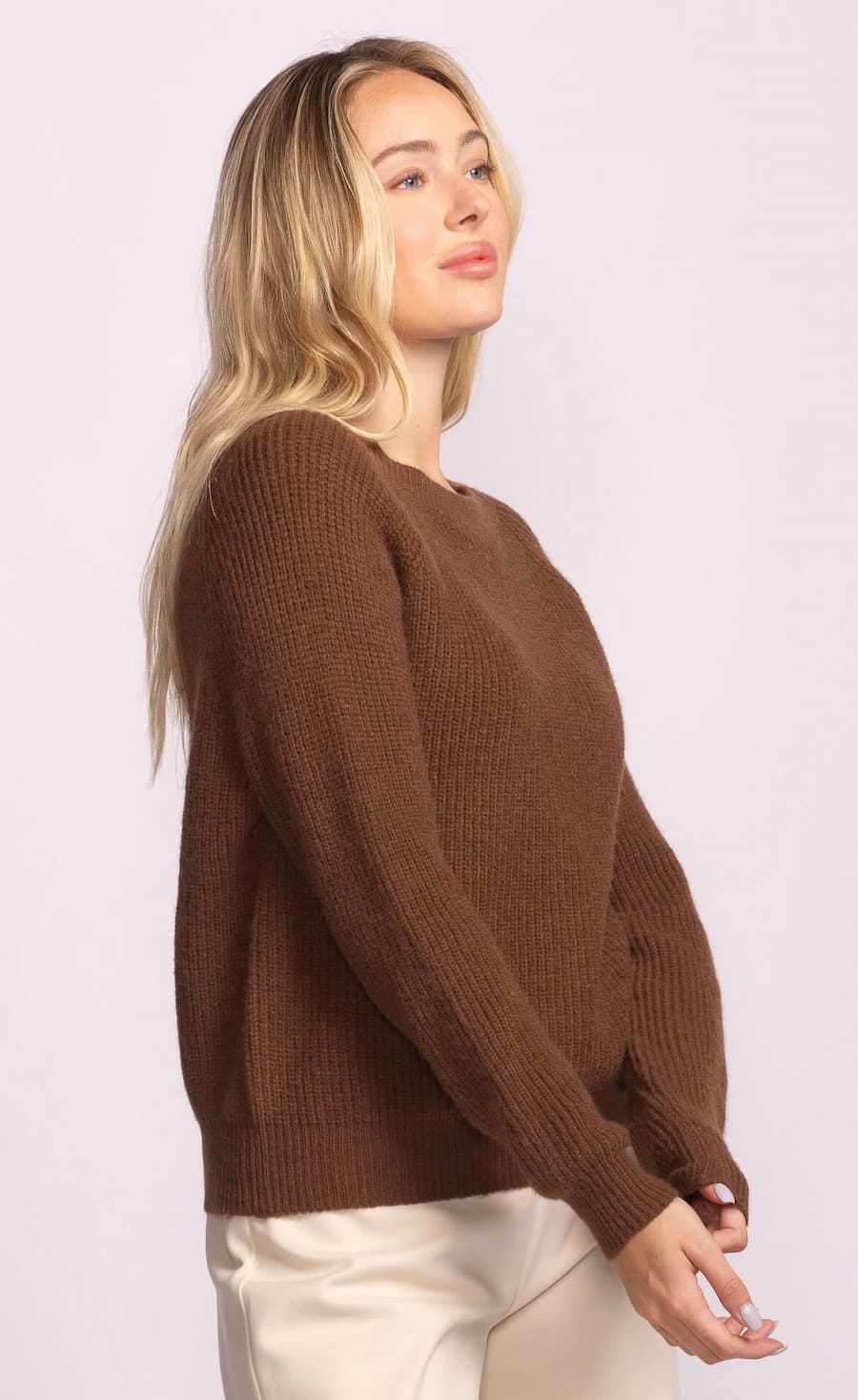 Woman wearing a brown sweater against a white background