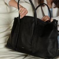woman holding black pixie mood amara weekender on white sofa, lemonberry aurora