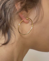 Jenny Bird Icon Hoops Small in gold — front and back views on model, Lemonberry Aurora — polished 14 K gold hoops with full-circle design shown in motion.