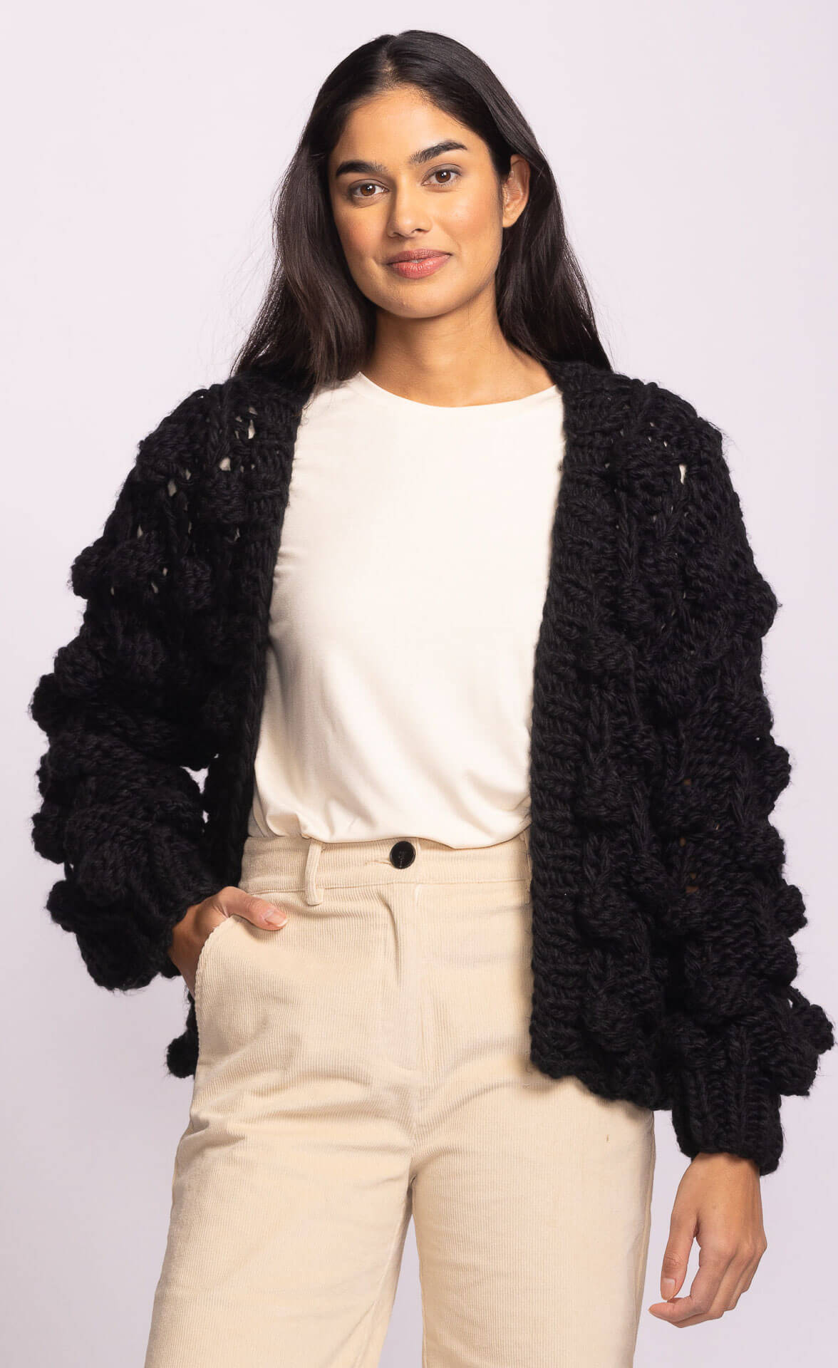 Statement Raya Sweater in black by Pink Martini, chunky knit cardigan with sculpted bubble sleeves, styled over a white top – available at Lemonberry online and in Aurora.