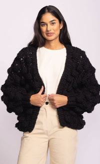 Model wearing Pink Martini Raya Sweater in black chunky knit with oversized bubble sleeves, open-front design – available at Lemonberry Aurora.