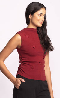 Side view of red Rosslie sleeveless knit top featuring floral appliqué details.