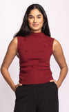 Front view of red Rosslie knit sleeveless top with raised floral details, styled with black pants.