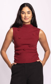 Front view of red Rosslie knit sleeveless top with raised floral details, styled with black pants.