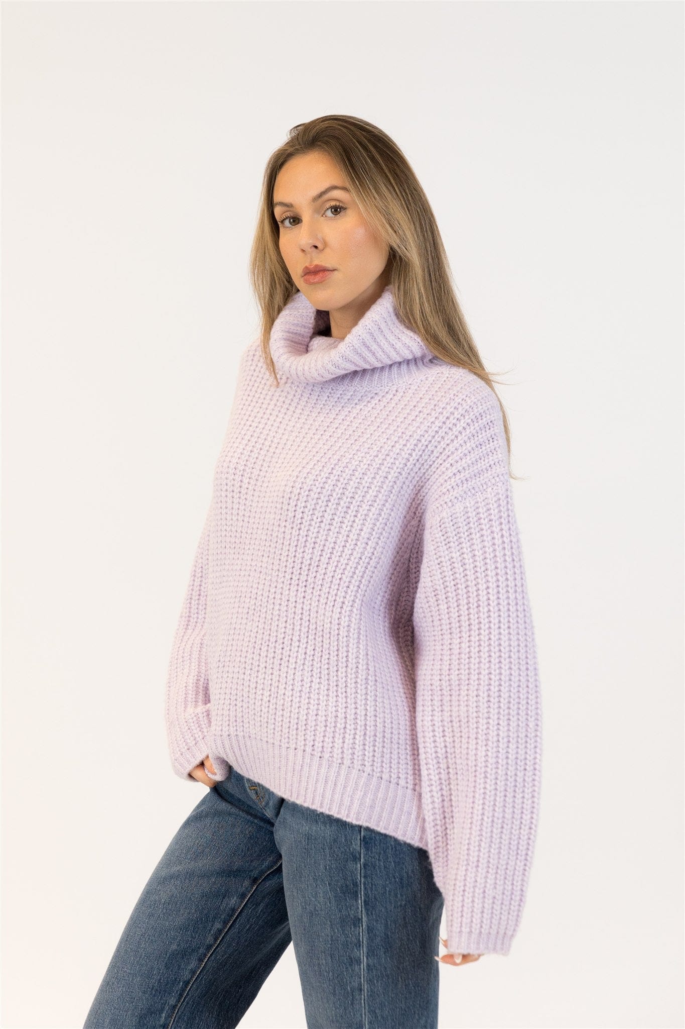 Side view of lilac SAHAR sweater by Lyla + Luxe, model with long hair wearing relaxed-fit ribbed knit and jeans