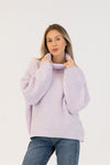 Model wearing lilac Lyla + Luxe SAHAR sweater facing front, holding ribbed turtleneck with both hands, styled with blue jeans, white backdrop