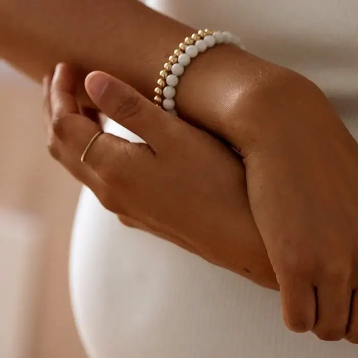 Close-up of moonstone and gold beaded bracelet stacked on wrist — available at Lemonberry