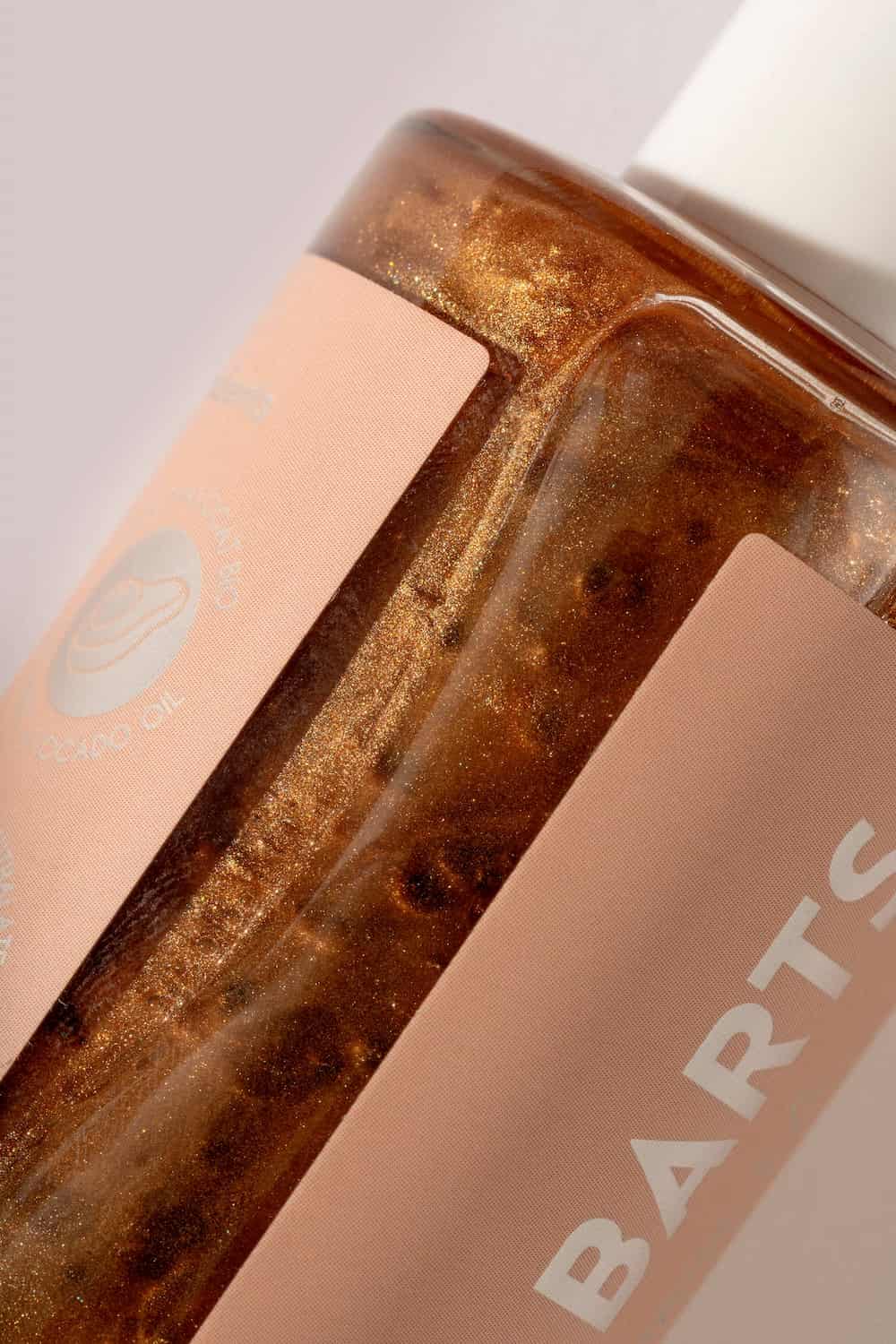 Detail of St. Barts dry shimmering oil label and bronze oil inside glass bottle.