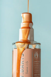 Bronze St. Barts dry shimmering body oil pouring from pump, showing luminous texture and glow.
