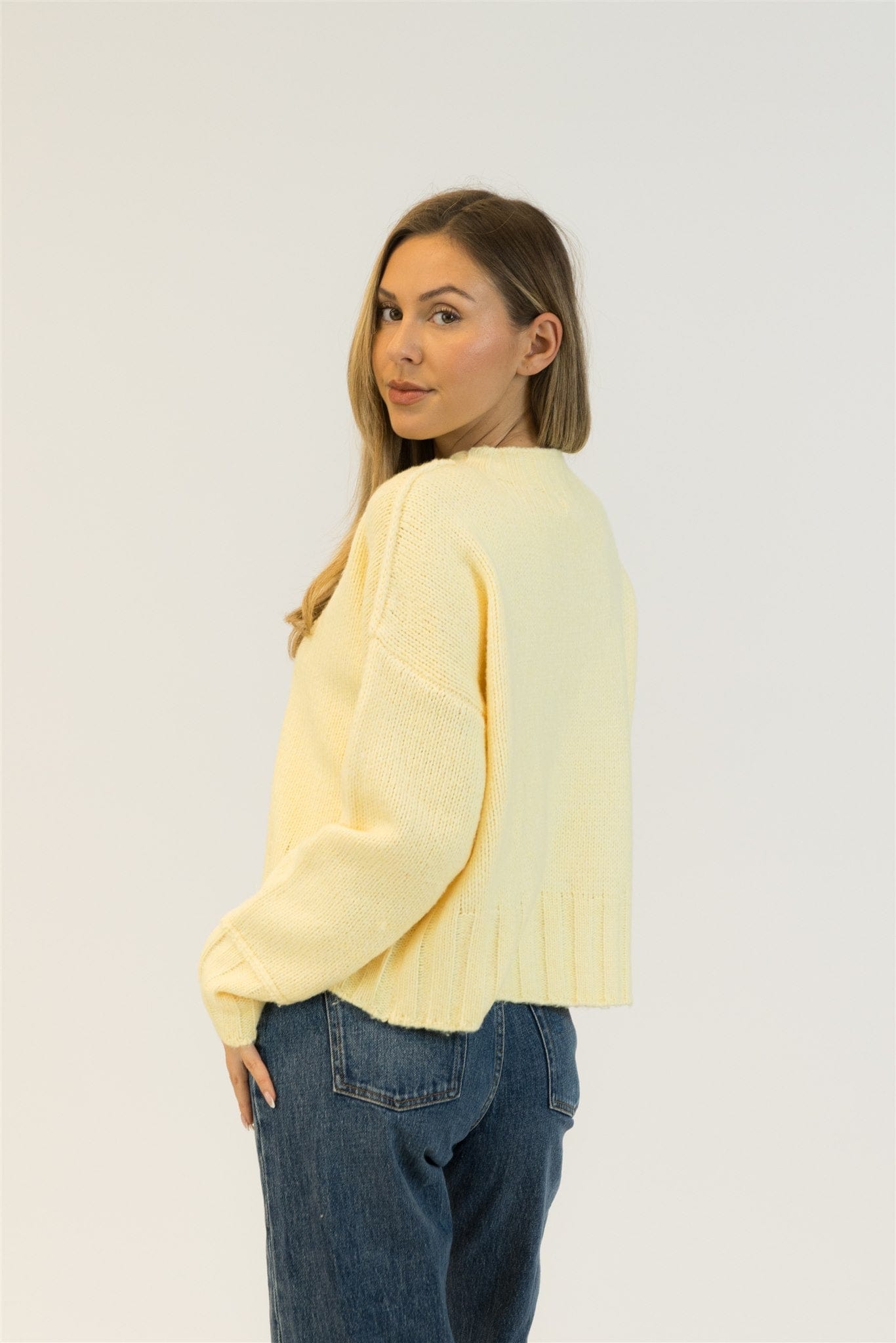 Back view of model wearing the Lemon Drop Timmy sweater with medium denim.