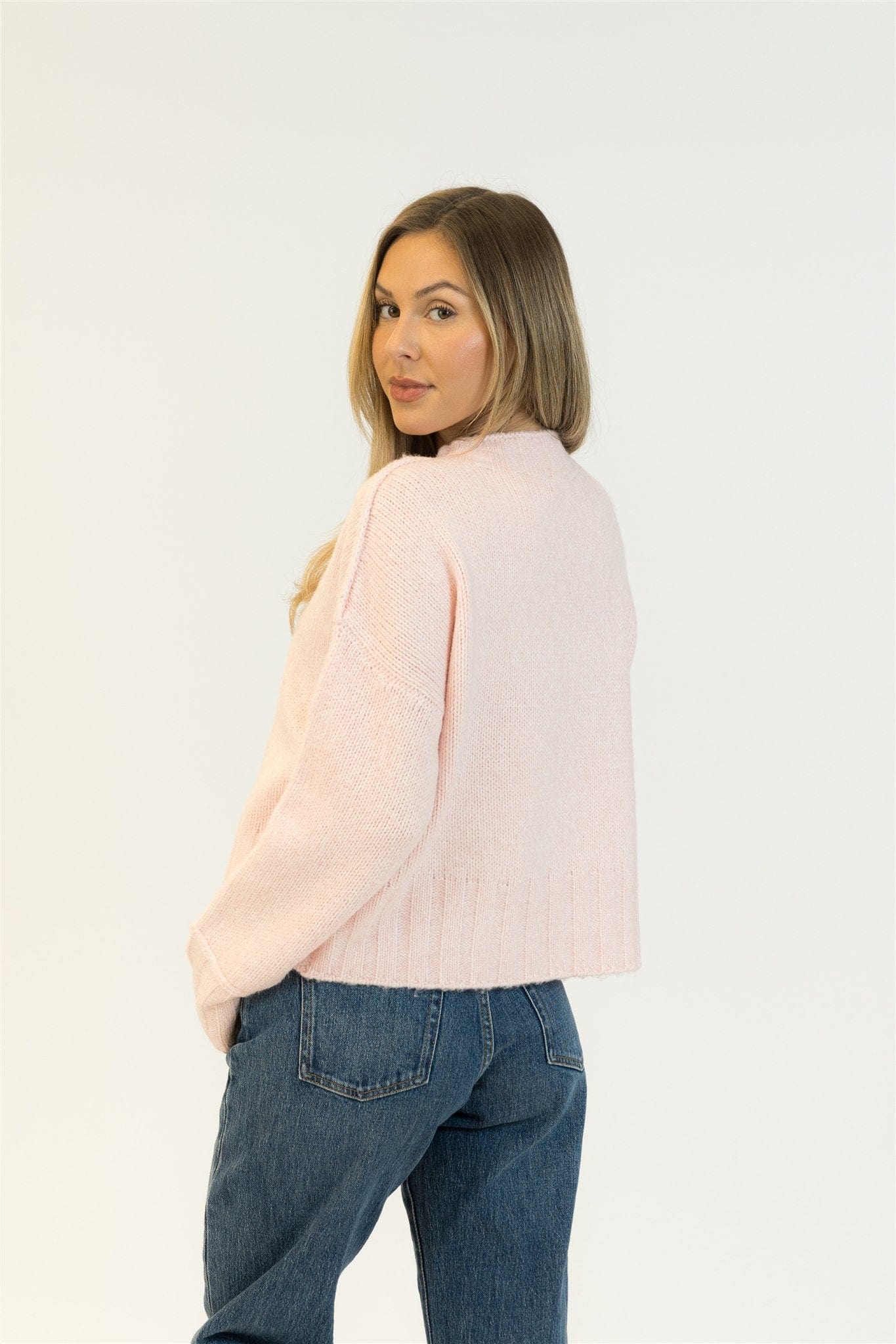 Rear view highlighting the sweater’s cozy drape and soft pink hue.

