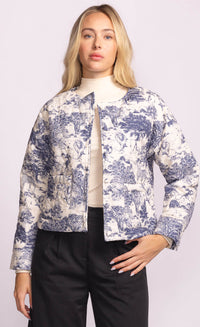 Woman wearing the Toulon Jacket by Pink Martini, front view with blue and cream safari print on padded fabric, styled with black trousers
