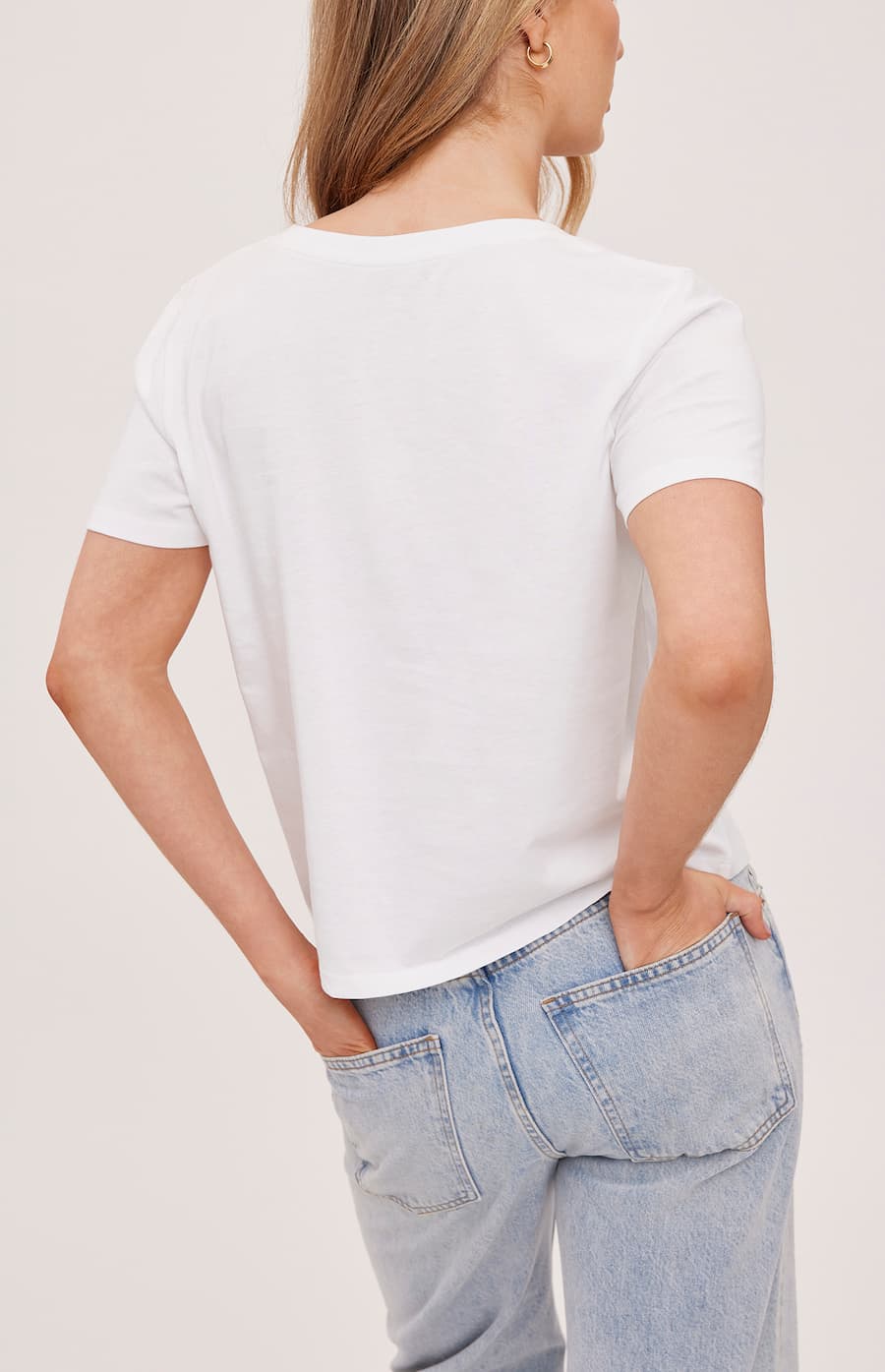 Person wearing a white t-shirt and light blue jeans on a plain background