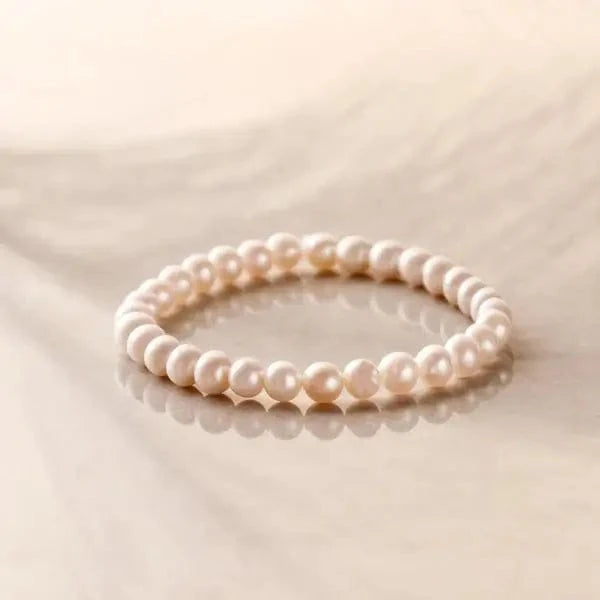 White pearl gemstone bracelet on reflective marble surface

