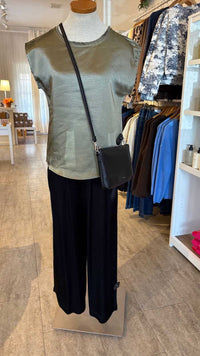 Mannequin wearing a green Willow top by Melissa Nepton and black pants with a crossbody bag inside Lemonberry