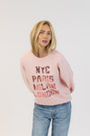 Model tilting forward in Lyla + Luxe Yassie sequin pullover with balloon sleeves and NYC, Paris, Milan, London sequins
