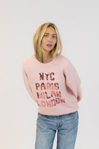 Model tilting forward in Lyla + Luxe Yassie sequin pullover with balloon sleeves and NYC, Paris, Milan, London sequins