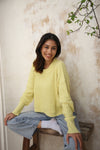 A yellow waffle-knit sweater paired with denim jeans, featuring a relaxed fit and fold-back cuffs. Available at Lemonberry, Aurora, ON
